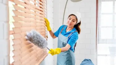 A professional cleaning a window blind, showing window blinds maintenance for home or office