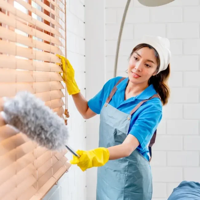 A professional cleaning a window blind, showing window blinds maintenance for home or office