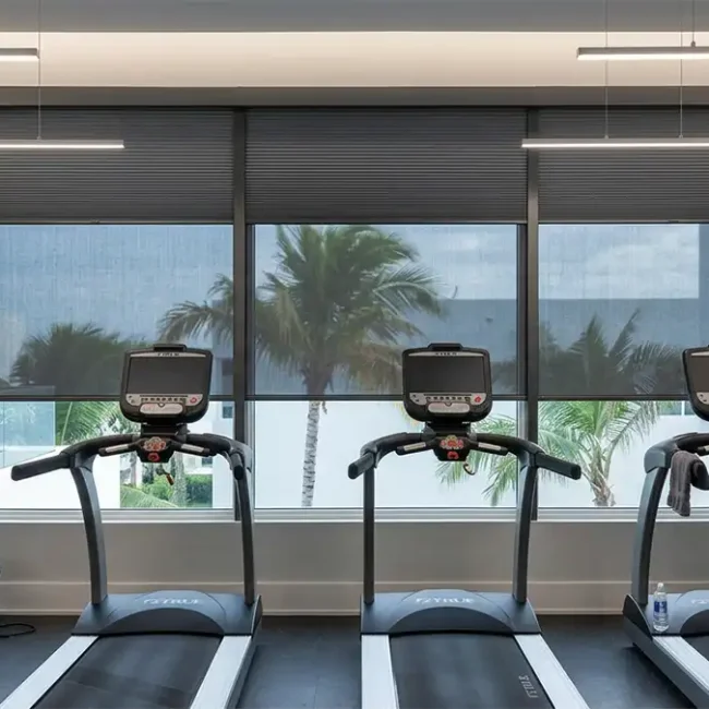 Modern gym interior with custom blinds on large windows, providing privacy, controlling light, and enhancing comfort and style