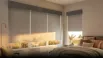 Light gray roller blinds filtering sunlight in a modern bedroom
