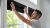 Homeowner installing roller blinds on a window with proper alignment for a secure fit
