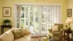 White vertical blinds covering a large living room patio door with natural light and modern home décor